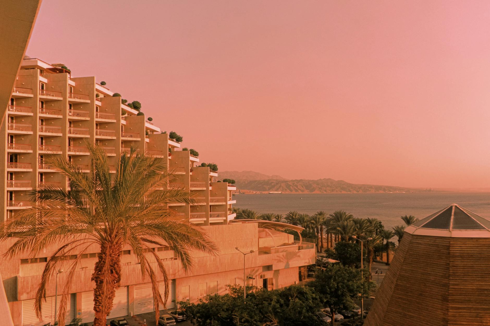 Nadmorski ośrodek wypoczynkowy o zachodzie słońca z palmami i morzem w tle