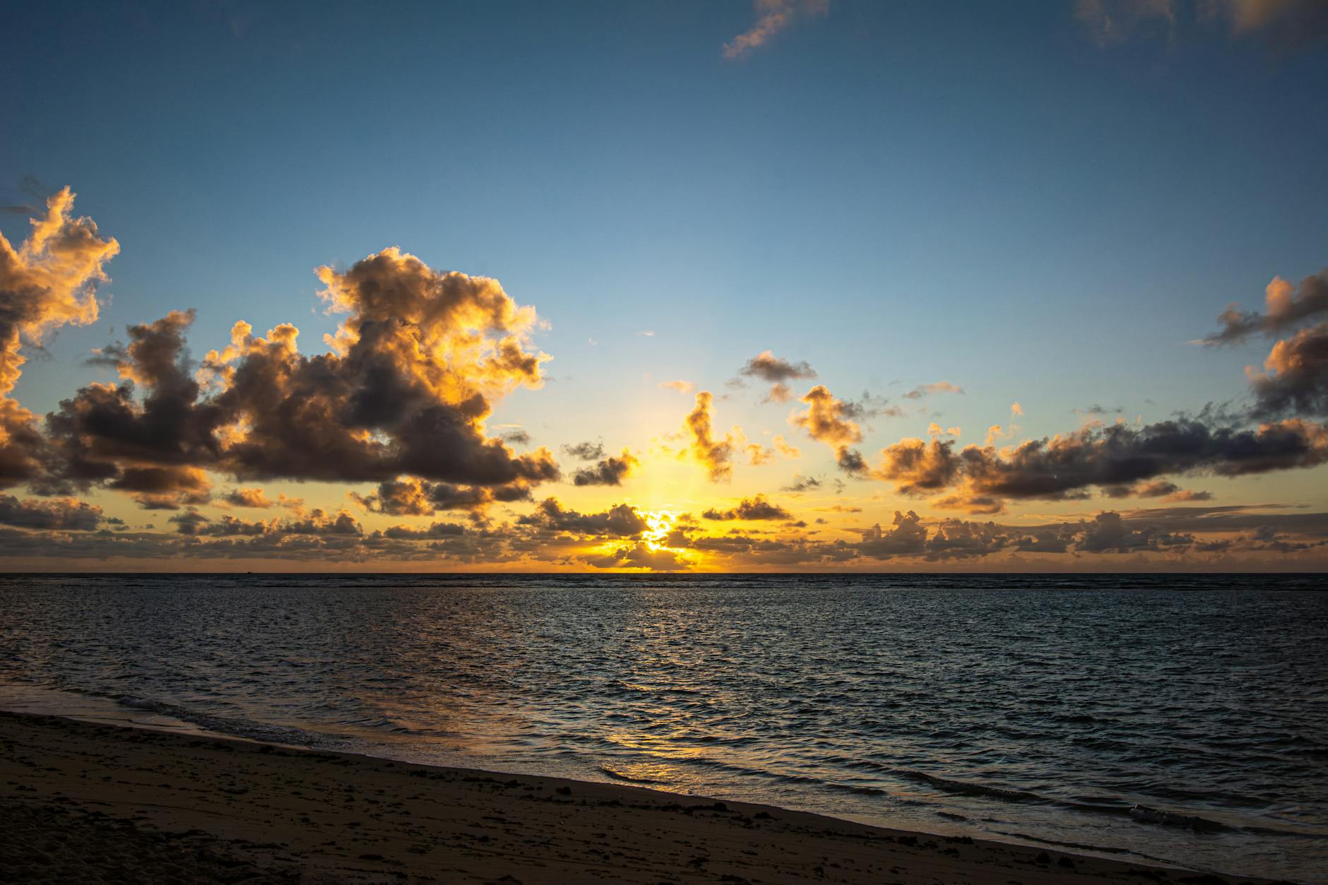 Zachód słońca nad spokojnym morzem i pustą plażą z kolorowymi chmurami