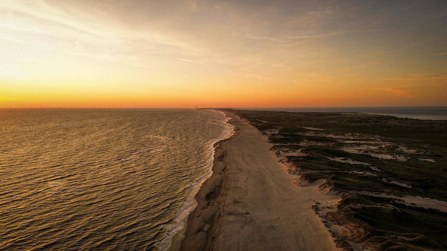 Zachód słońca nad szeroką plażą i Bałtykiem w Dziwnowie z lotu ptaka