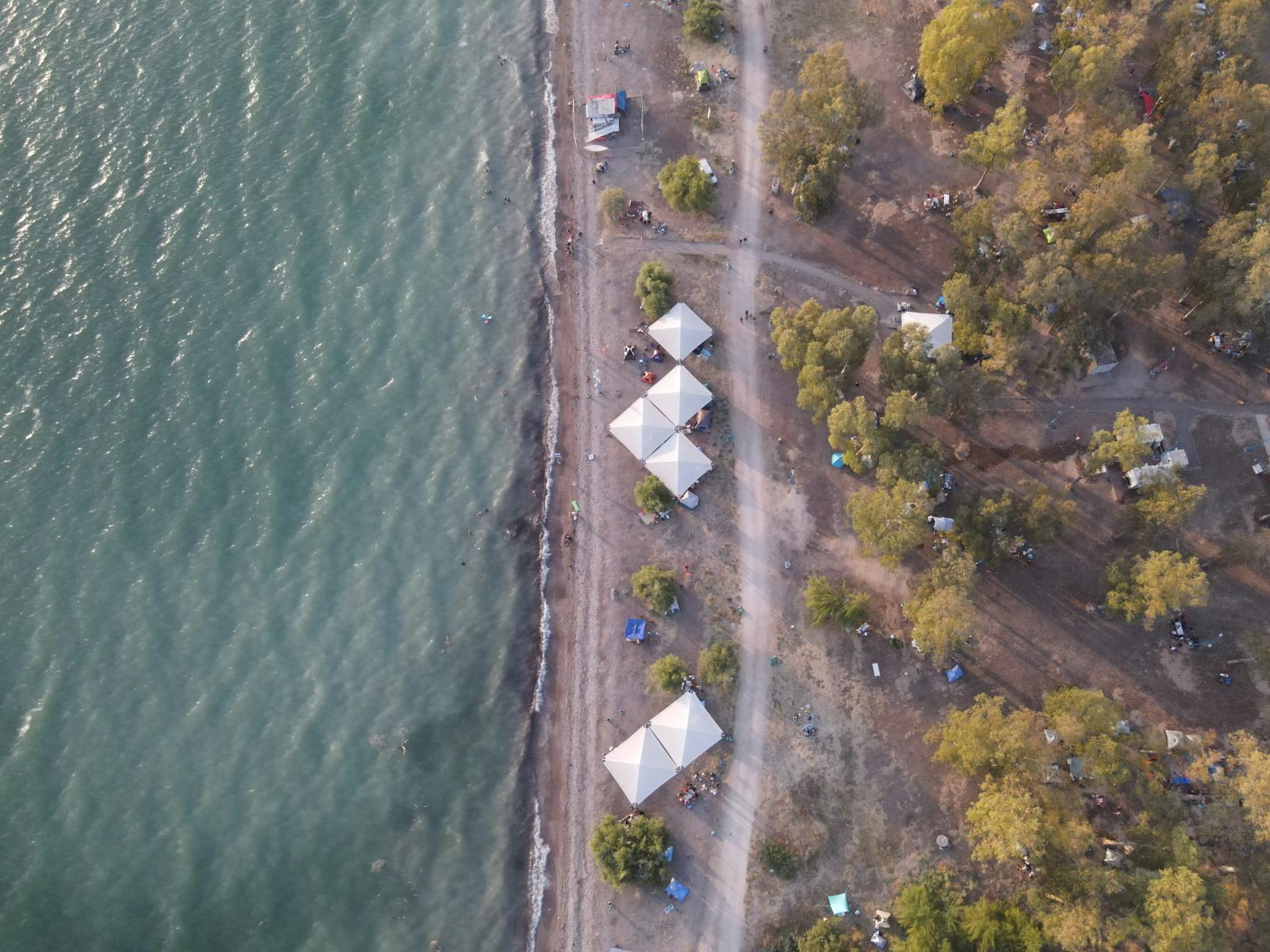 Widok z góry na małe pola namiotowe przy plaży w otoczeniu drzew