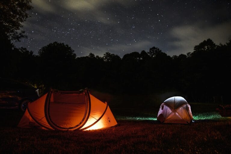 Rozświetlone namioty na nocnym kempingu pod gwiazdami